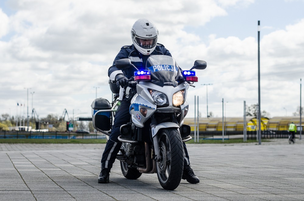 Policyjny motocykl z siedzącym na nim motocyklistą w kasku