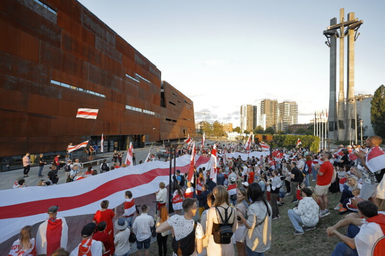 marsz pod ECS, ludzie zebrani pod budynkiem, w dłoniach niosą flagi Białorusi