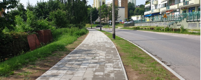widok na nowo wybudowany chodnik wzdłuż jezdni w tle zieleń oraz bloki