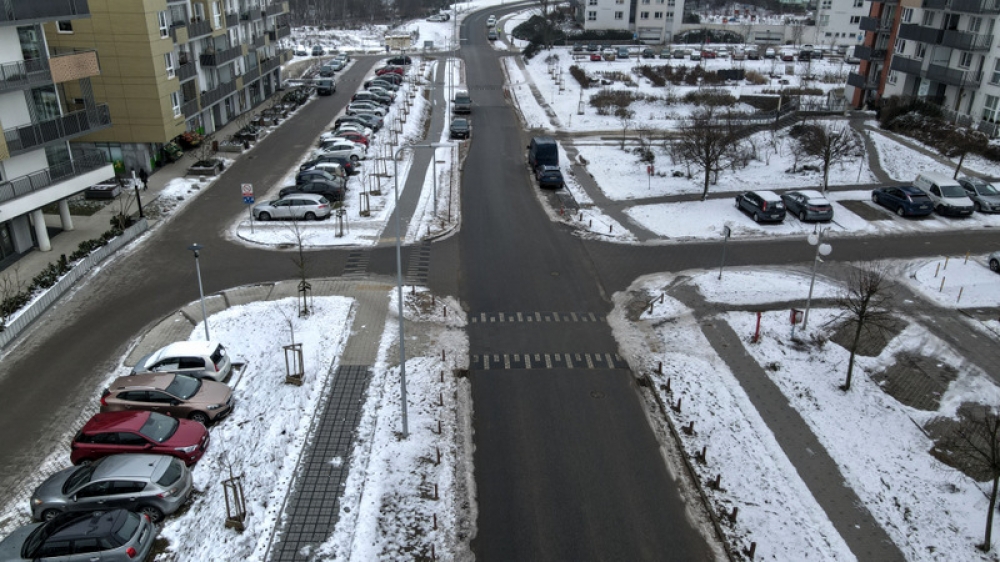widok na zmodernizowaną, ośnieżoną jezdnie z miejsami parkingowymi, w koło zabudowania mieszkalne