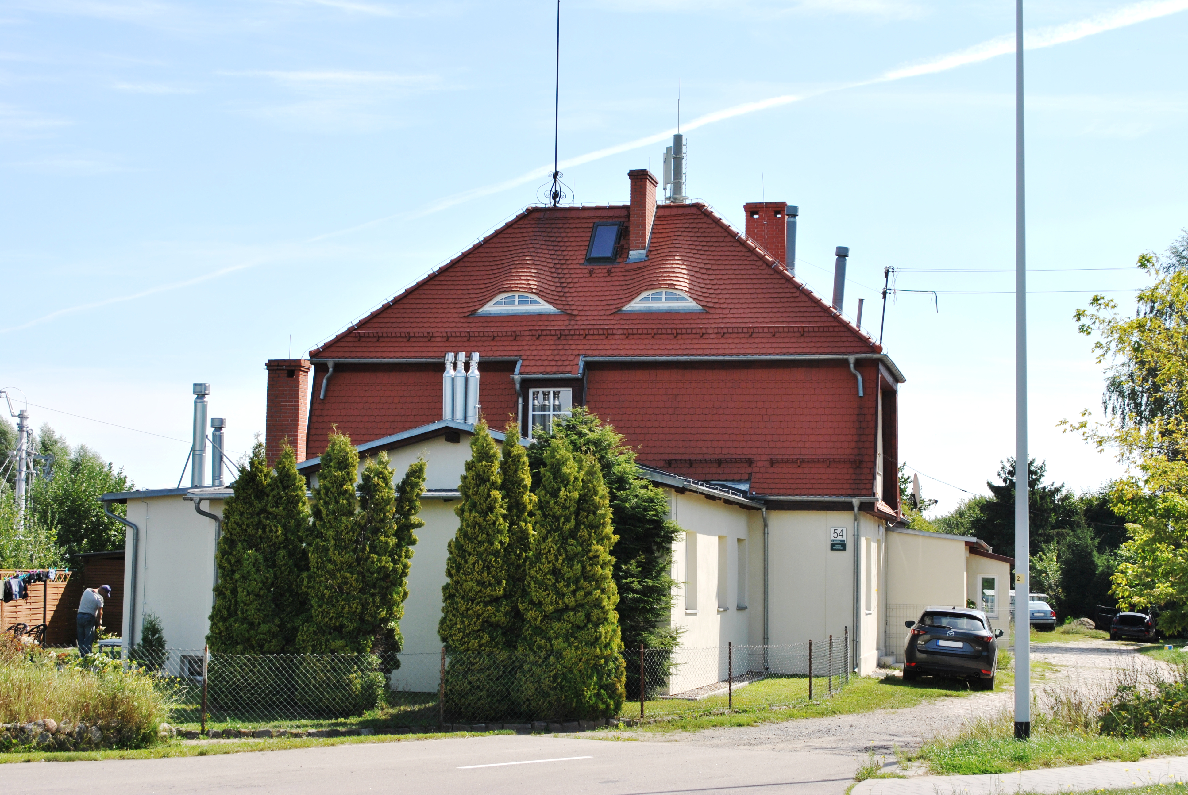 Widok wyremontowanego dachu mansardowego budynku głównego, krytego dachówką ceramiczną typu karpiówka.