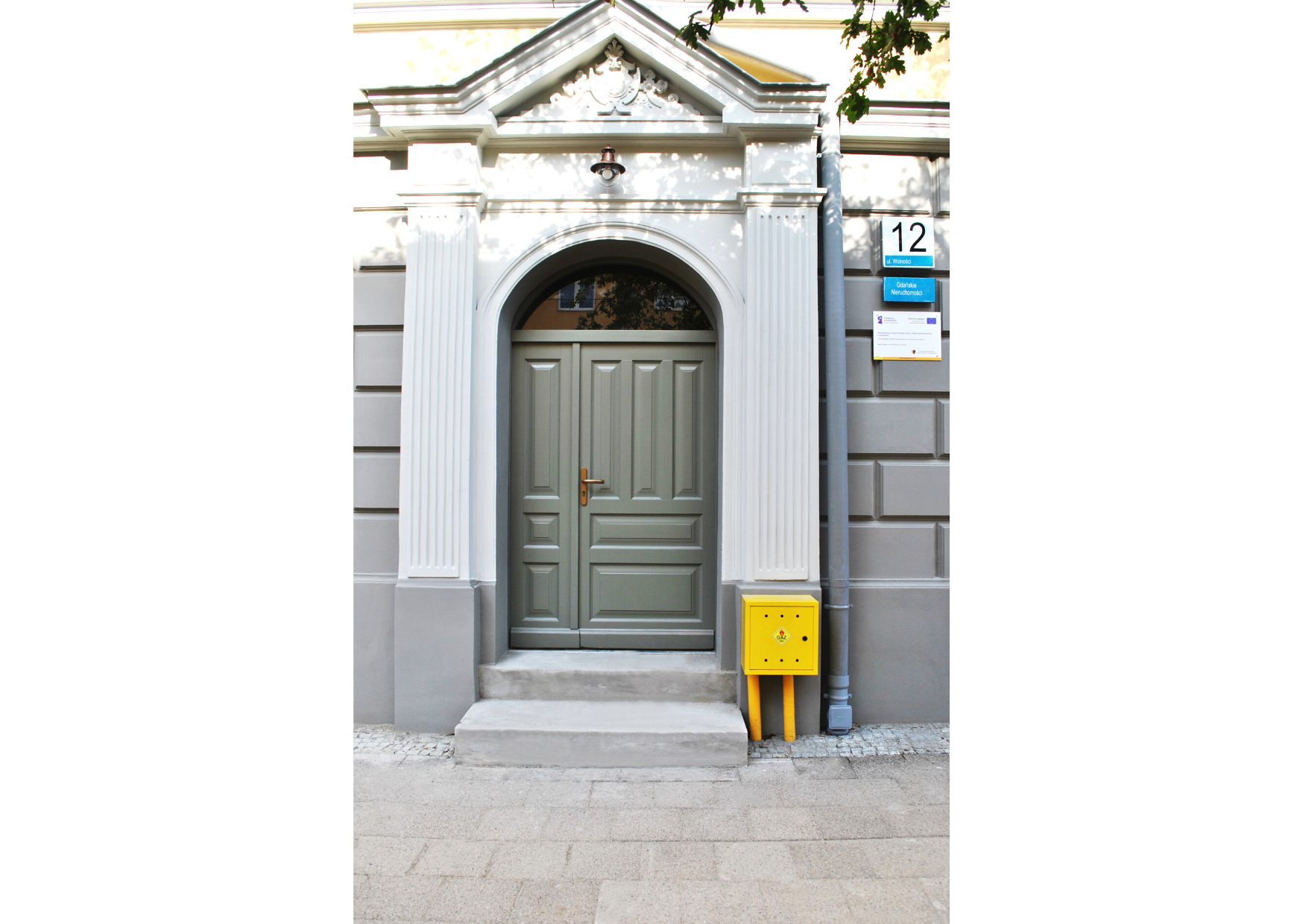 Portal wejściowy do budynku z odrestaurowanymi detalami architektonicznymi.