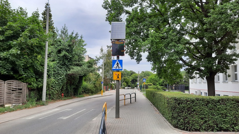 widok na wyświetlacz prędkości umieszczony przy drodze na chodniku, wkoło zieleń