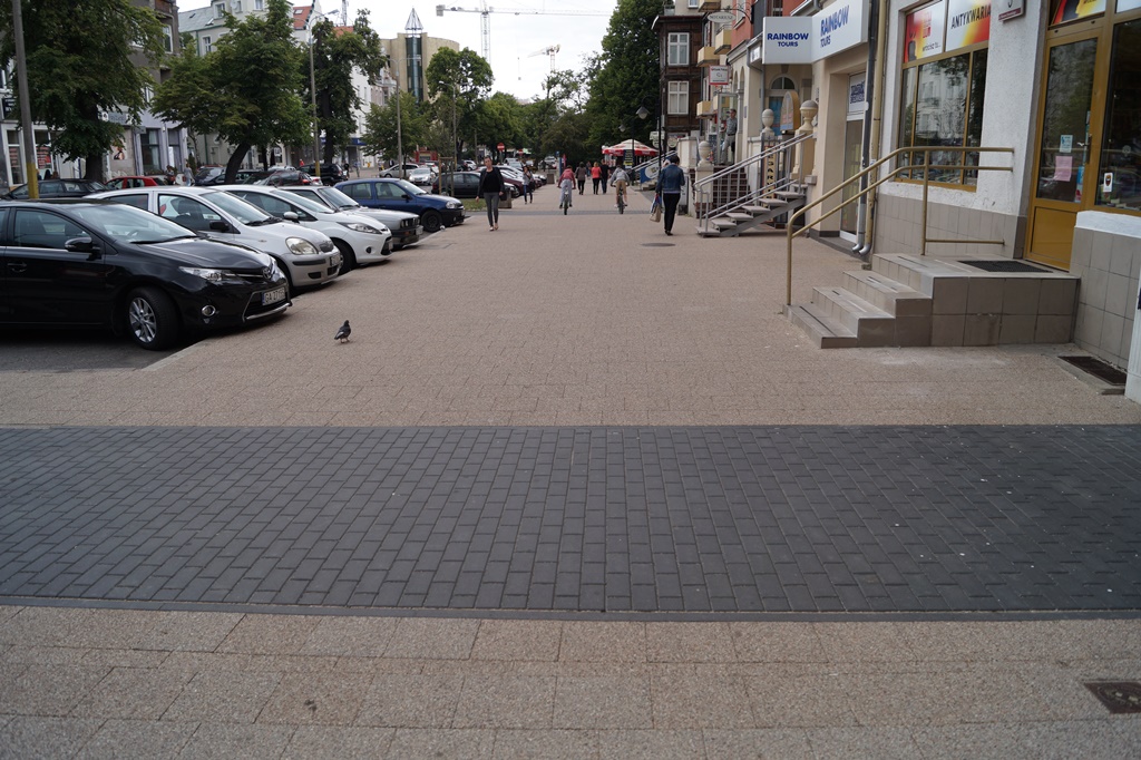 widok na nowy chodnik z kostki w mieście, w tle samochody, sklepy, ludzie