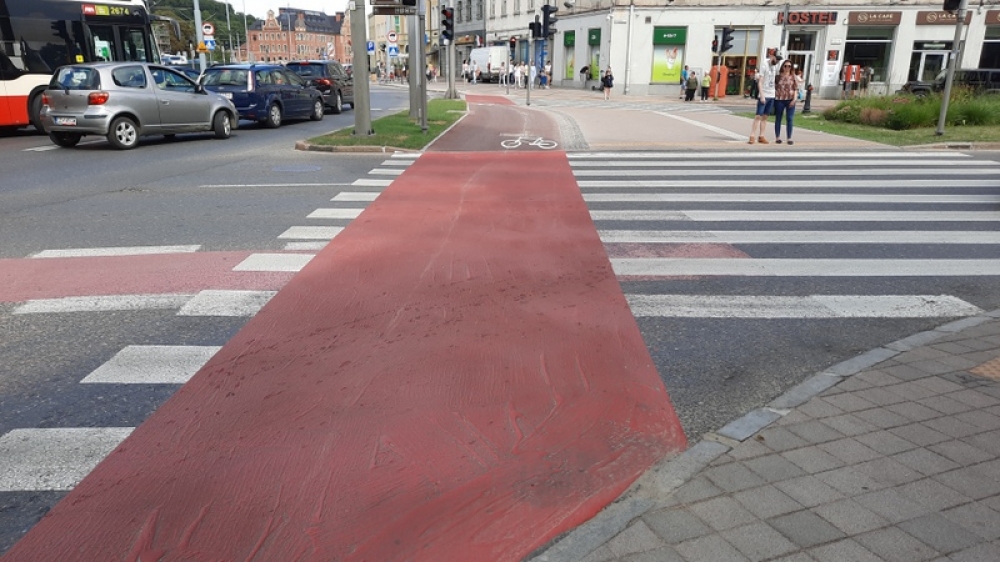 czerwona ścieżka rowerowa, piesi, samochód