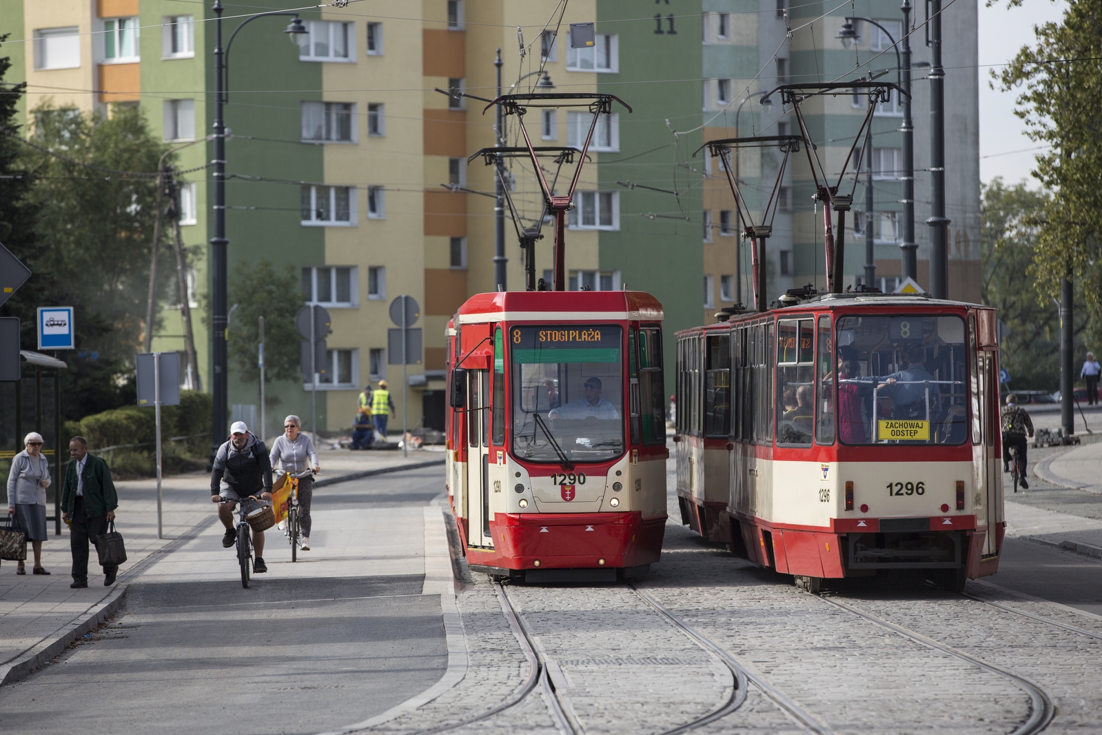 Na zdjęciu widać fragment ul. Siennickiej, na której mijają się dwa tramwaje. Po lewej stronie przystanek wiedeński, przez który przejeżdża dwoje rowerzystów