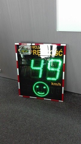 elektroniczny znak, pokazujący prędkość 49 km/h oraz uśmiechniętą buźkę w zielonym kolorze 
