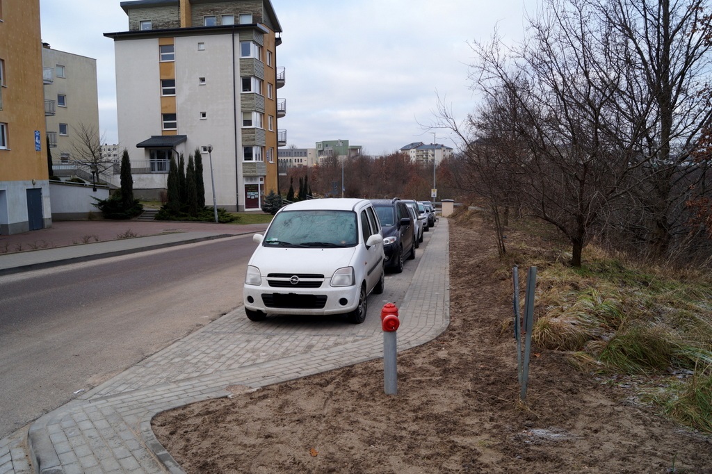 widok na powstałe miejsca parkingowe wzdłuż drogi, widoczne zaparkowane auta